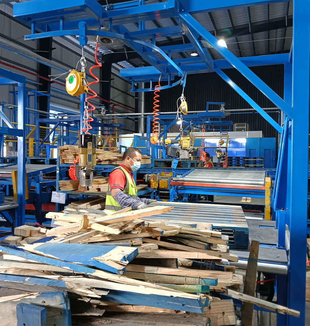 A worker in a factory processing wooden pallets and scrap.